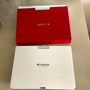 Two 2000 era Polaroid portable DVD players. One silver and one red.